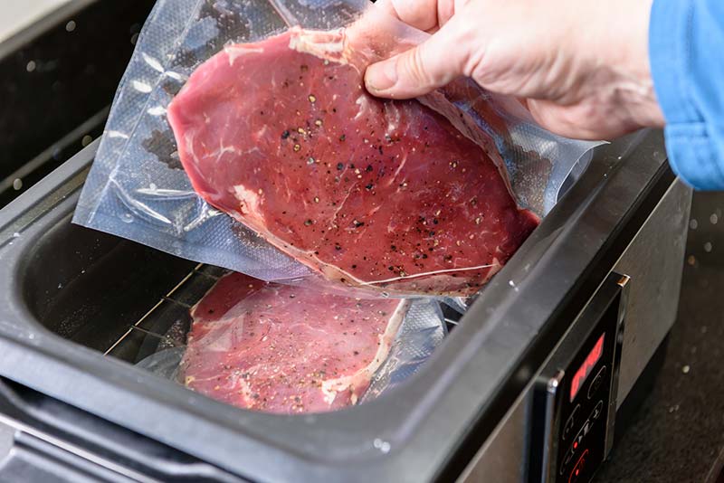 vakuumiertes Stück Fleisch wird in Sous Vide Garer gelegt